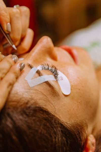 Woman applying eyelash extensions to client